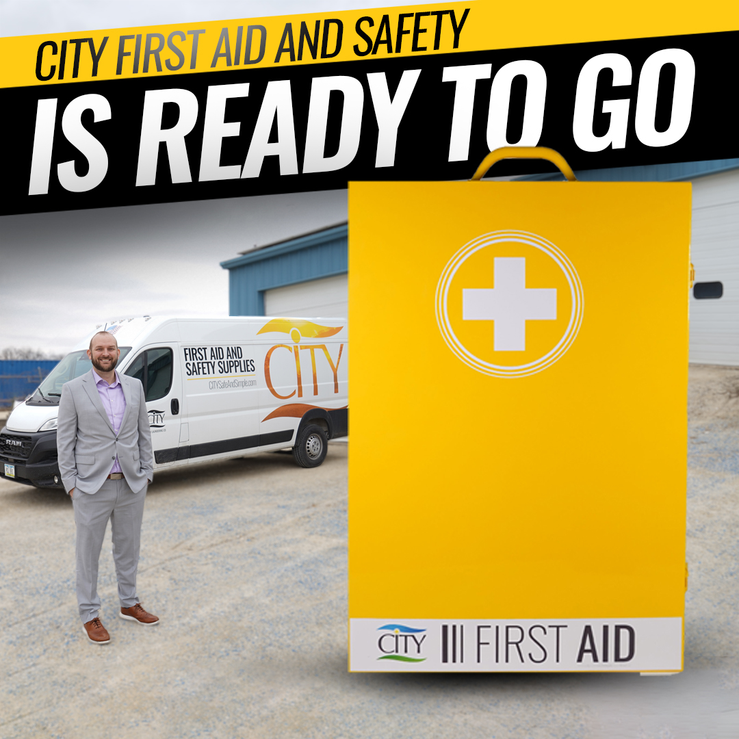 CITY First Aid and Safety representative stands by a service van and large yellow first aid cabinet with the text “Ready to Go.”